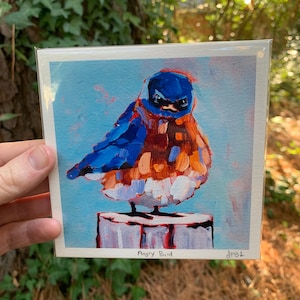 May include: A bluebird with an angry expression is painted in a colorful, abstract style. The bird is perched on a wooden stump against a light blue background. The painting is titled "Angry Bird".