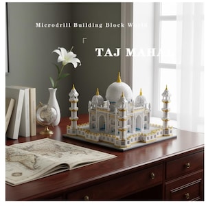May include: A white and gold Taj Mahal microdrill building block model. The model is on a dark wood desk with a globe, books, and a vase with a white flower. The text "TAJ MAHAL" is displayed.