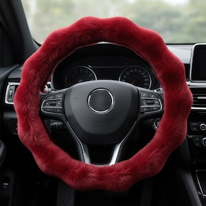 May include: A plush, red steering wheel cover. The cover is made of a soft, furry material and is designed to fit over a standard car steering wheel. The cover has a wavy, textured design and adds a touch of style to the car's interior.