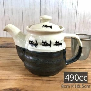 May include: A ceramic teapot with a black and white design. The teapot features a black base, a white upper section with black cat illustrations, and a matching lid. The teapot is approximately 3.1 inches wide and 3.7 inches high.