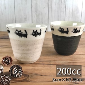 May include: Two ceramic cups with black cat illustrations. One cup is beige with a speckled texture, the other is dark gray. Both have a white rim with black cat designs. Each cup is 8cm wide and 7.5cm high, with a capacity of 200cc.