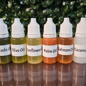 May include: Six small clear plastic dropper bottles with white caps, each containing a different colored oil. The labels are printed with the text Avocado Oil, Olive Oil, Sunflower Oil, Palm Oil, Salmon Oil, and Coconut Oil in black ink.
