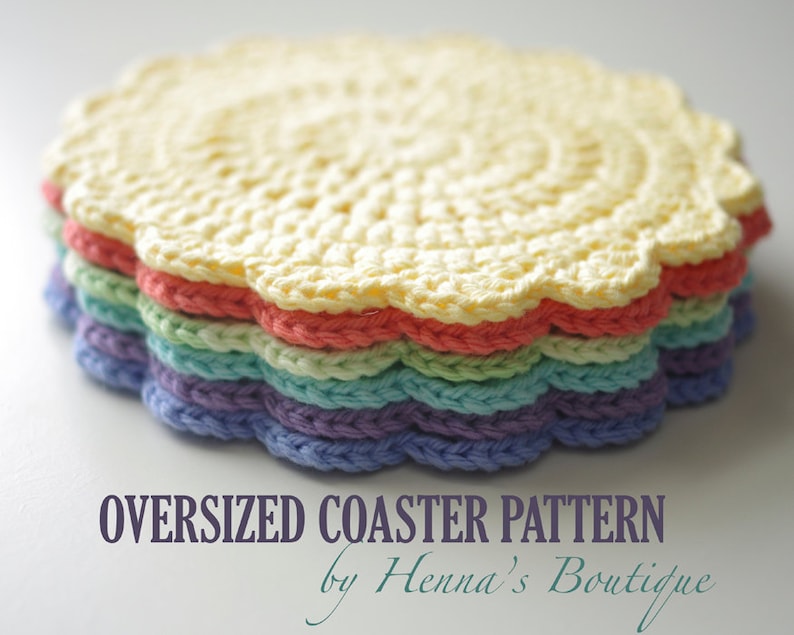 May include: A stack of oversized, crocheted coasters in a variety of pastel colors. The coasters have a scalloped edge and are in shades of yellow, red, green, blue, and purple. Text on the image reads "OVERSIZED COASTER PATTERN by Henna's Boutique."