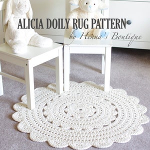 May include: A white crocheted doily rug with a scalloped edge. The rug is on a light gray carpet and there are two white chairs with stuffed animals on them. The text "Alicia Doily Rug Pattern - by Henna's Boutique" is visible in the image.