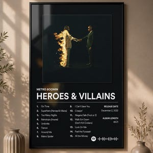 Peut inclure: Une affiche murale encadrée en noir présentant la pochette de l'album Heroes & Villains de Metro Boomin. Le design comprend une liste de 15 chansons, la date de sortie du 2 décembre 2022, une durée totale de 48:21 et un code Spotify.