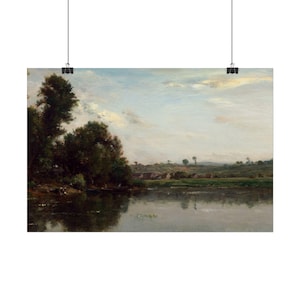 May include: A landscape print featuring a serene river scene with lush green trees on the left and a distant village under a cloudy sky. The artwork is mounted and held by black clips.