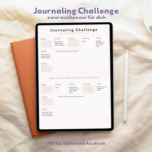 Peut inclure: Une tablette numérique affichant un modèle de défi de journalisation avec des invites quotidiennes. La tablette est à côté d'un carnet orange et d'un stylet blanc. Le texte sur la tablette indique "Journaling Challenge" et "PDF pour tablette et impression."
