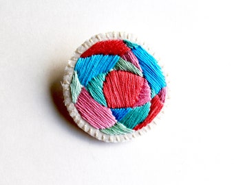 Hand embroidered brooch with round geometric design in bright pinks, blues and green colors on cream muslin Fall fashion An Astrid Endeavor