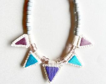 Hand embroidered triangle pendant necklace on long silver leather cord with glass beads in gray, blue, purple and pink An Astrid Endeavor