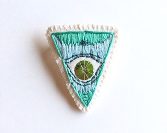 Hand embroidered brooch green mystic eye with sparkles and sequin on organic muslin and cream felt backing Fall trends An Astrid Endeavor