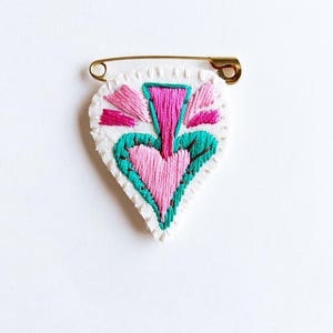 Embroidered heart brooch pink teal and red metallic threads on bright cream muslin with cream felt back gold tone safety pin Valentines Day