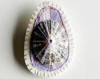 Hand embroidered brooch abstract design using lavender variegated threads and limpet shell An Astrid Endeavor contemporary fiber jewelry