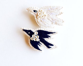 Embroidered bird brooch in black or white cotton thread white shell beads on muslin and felt backing An Astrid Endeavor contemporary craft