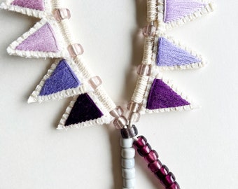 Bolo style long necklace with hand embroidered triangle pendants on thick silver leather cord pinks purples and grays with glass beads