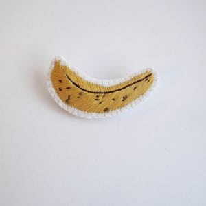 Embroidered banana brooch on cream muslin with cream felt backing yellow and brown cotton thread An Astrid Endeavor kitsch fashion
