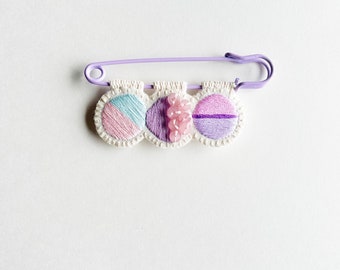 Hand embroidered pin for sweaters with large lavender safety pin pinks blue lavender threads and rose quartz beads on cream muslin