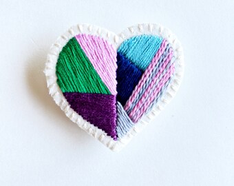 Hand embroidered heart brooch geometric design with pink, blue, purple, green and gray threads on cream muslin An Astrid Endeavor gift guide