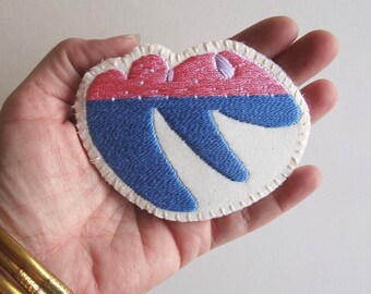 Hand embroidered brooch with unique geometric design using shiny pink and bright blue cotton thread An Astrid Endeavor textile jewelry