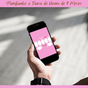 May include: A black smartphone displaying a pink screen with white illustrations and text. The phone is held in a person's hand, with a black watch visible on the wrist. The text at the top reads "Planificador y Diario de Verano de 4 Meses."