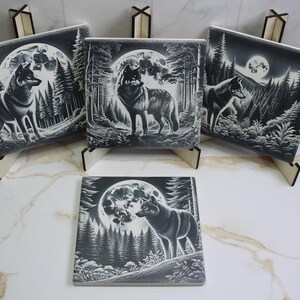 May include: Four square decorative tiles with a black and white wolf design. The tiles feature a wolf in a forest setting with a full moon in the background. The tiles are displayed on small wooden easels.