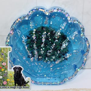 May include: A blue resin tray with a scalloped edge, filled with glitter and a central design of green leaves. The tray has a sticker that says "Please Read The Description" and "This item is made from Resin" with a picture of a black Labrador.