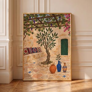 Op de afbeelding: Een ingelijst schilderij met een mediterrane binnenplaats met een centrale olijfboom, een stenen bank met kussens met patronen, een groene deur en drie keramische vazen op een stenen terras onder een met paarse druiven begroeid prieel.