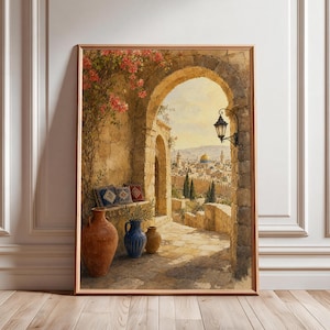 May include: A framed wall art print depicting a stone archway overlooking a city with a golden dome. The scene features a terracotta vase, a blue patterned vase, and a small yellow vase on a stone floor, with pink flowers hanging from the arch.