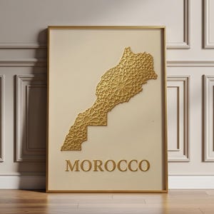 May include: A rectangular wall art piece in a gold frame featuring a cream-coloured background. A gold-coloured, textured map of Morocco is centred, filled with intricate geometric patterns. The word MOROCCO is printed in gold below the map.