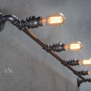 May include: A black metal pipe light fixture with five Edison bulbs. The fixture is mounted to a wall and has a horizontal arm with four bulbs and a vertical arm with one bulb.
