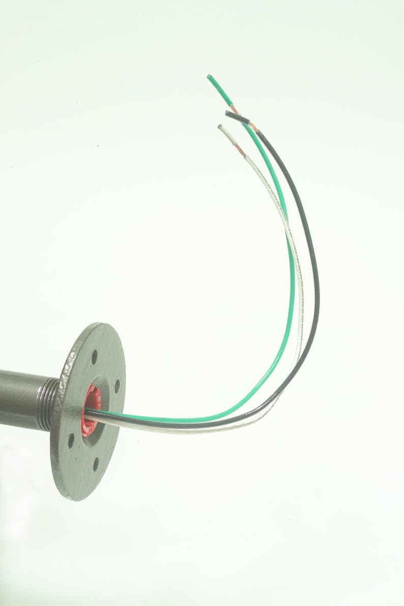 May include: A close-up of a gray metal pipe fitting with three wires coming out of it. The wires are green, black, and white.