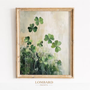 May include: A framed painting of green shamrocks. The artwork shows shamrocks with visible brushstrokes against a soft, neutral background. The frame is a light gold colour, and the artwork is signed "LOMBARD PRINTS".