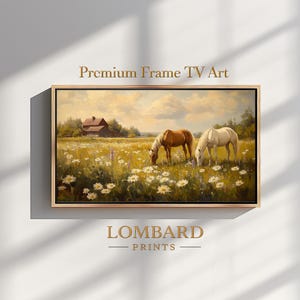 May include: Framed artwork featuring a pastoral scene with two horses grazing in a field of wildflowers. A barn is visible in the background under a cloudy sky. The text "Premium Frame TV Art" and "LOMBARD PRINTS" are displayed.
