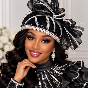 Peut inclure: Un chapeau pillbox noir orné de rayures verticales en sequins argentés, d'une large bande de cristaux transparents et d'un grand nœud en tulle noir décoré de perles blanches sur des tiges métalliques. Assorti de boucles d'oreilles et d'un vêtement noir.