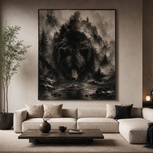 以下が含まれることがあります： 霧深い森の風景から現れるクマの顔を描いた、額入りの大きな白黒アートワーク。ベージュのコーナーソファの上に飾られており、装飾的なクッションが置かれている。暗い木製のコーヒーテーブルと鉢植えの植物が前景にある。
