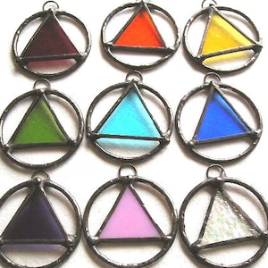 May include: Nine colorful stained glass pendants. Each pendant features a triangle within a circular frame. The triangles are in various colors: red, orange, yellow, green, blue, purple, pink, and white. The pendants are made of glass and metal.