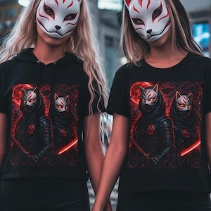 Może przedstawiać: Dwie czarne koszulki z krótkim rękawem z nadrukiem graficznym przedstawiającym dwie postacie w maskach lisa i ciemnej zbroi z jarzącymi się czerwonymi akcentami. Koszulki zestawiono z czarnymi spodniami. Każda postać ma na twarzy biało-czerwoną maskę lisa.