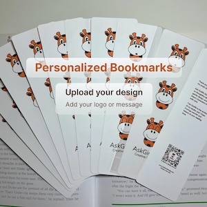 May include: A stack of white personalized bookmarks with a cartoon giraffe design. The text "Personalized Bookmarks" and "Upload your design" are displayed. The bookmarks are fanned out over an open book.