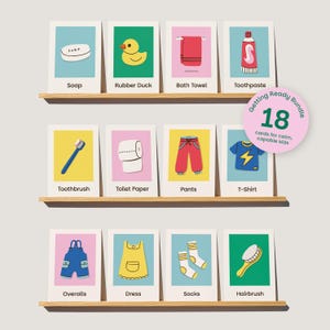 May include: A collection of 18 illustrated cards for children, including images of a rubber duck, a bath towel, and a T-shirt. The cards are arranged on wooden shelves, with a pink label that says "Getting Ready Bundle".