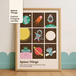 May include: A framed print with space-themed illustrations in a grid. It shows a planet, comet, rocket, astronaut, sun, moon, UFO, planet, and satellite. The text "Space Things" and related words are at the top and bottom of the print.