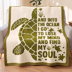 May include: A cream-colored crochet blanket featuring a large olive green sea turtle graphic on the left side and the text "AND INTO THE OCEAN I GO TO LOSE MY MIND AND FIND MY SOUL" in olive green, accented with small turtle and seaweed icons.