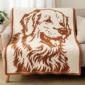 May include: A rectangular crochet blanket featuring a large, detailed portrait of a golden retriever dog. The design is created using a two-tone color scheme of cream and rust-brown yarn, with a matching rust-brown border framing the entire piece.