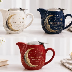 May include: Three ceramic teapots in white, navy blue, and red, each featuring a metallic silver lid and a gold crescent moon with a face, stars, and the text "NOCTURNE COLLECTION EST. 2026" printed on the side of the rounded body.