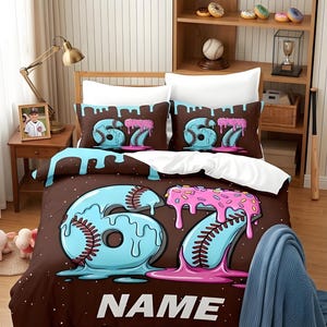 May include: A brown bedding set featuring a large light blue and pink number 67 graphic designed with baseball stitching and dripping icing, with the word NAME printed below. A round rug displays a baseball and a chocolate donut graphic.