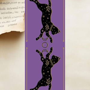 Peut inclure: Marque-page avec deux silhouettes de chats noirs sur fond violet. Les chats sont ornés de détails célestes et d'accents dorés. Le texte "etherrootsspiritual" et "williamstephaniesawyero" est en bas.
