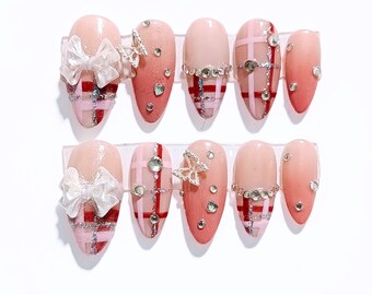 Unghie finte a quadri rosa con fiocco e strass, unghie luccicanti di lusso, forma a mandorla