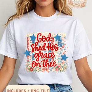 May include: White t-shirt featuring the phrase "God shed His grace on thee" in red script, surrounded by blue stars and floral accents. The design incorporates red, white, and blue patterns, with the text "INCLUDES : PNG FILE" at the bottom.