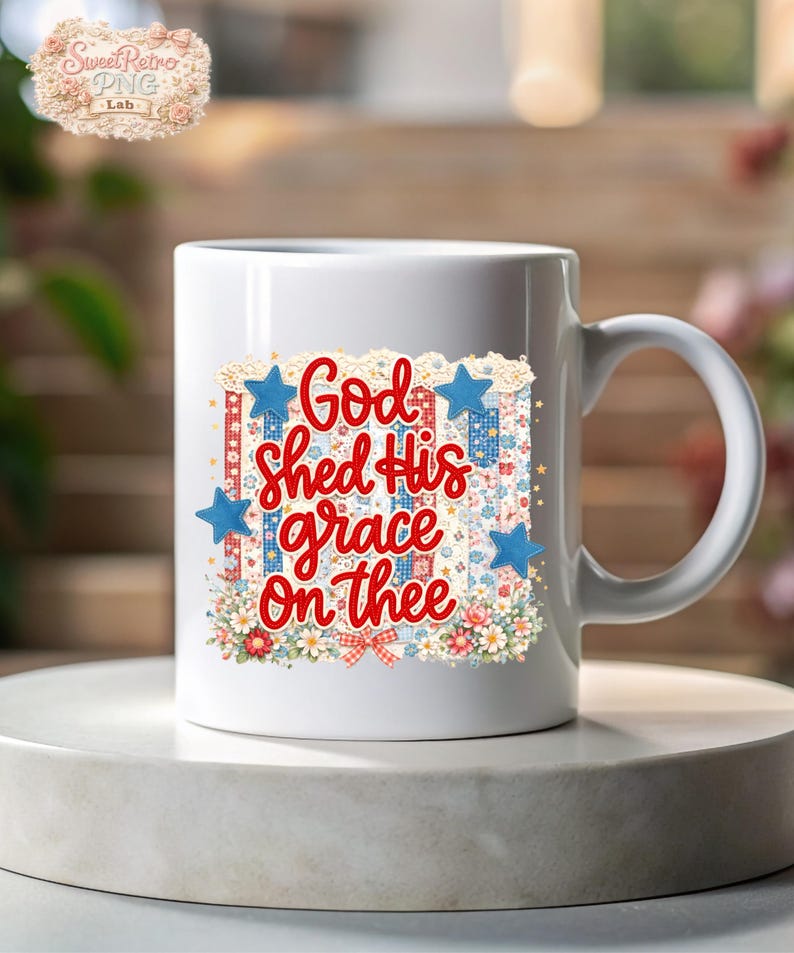 May include: White ceramic mug with a patriotic design. The mug features the text "God shed His grace on thee" in red script, surrounded by blue stars, floral patterns, and a red, white, and blue color scheme.
