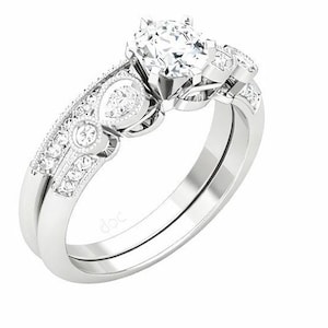 Peut inclure: Un ensemble de bagues de fiançailles en argent, avec une grosse pierre précieuse ronde et transparente au centre. La bande est ornée de petites pierres scintillantes et de filigranes décoratifs. L'ensemble comprend une alliance assortie.