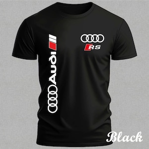 Könnte beinhalten: Schwarzes T-Shirt mit dem Audi-Logo und den Buchstaben "RS" in Weiß und Rot. Das Wort "Audi" ist vertikal in Weiß auf der linken Seite aufgedruckt. Das Wort "Black" ist kursiv am unteren Rand gedruckt.