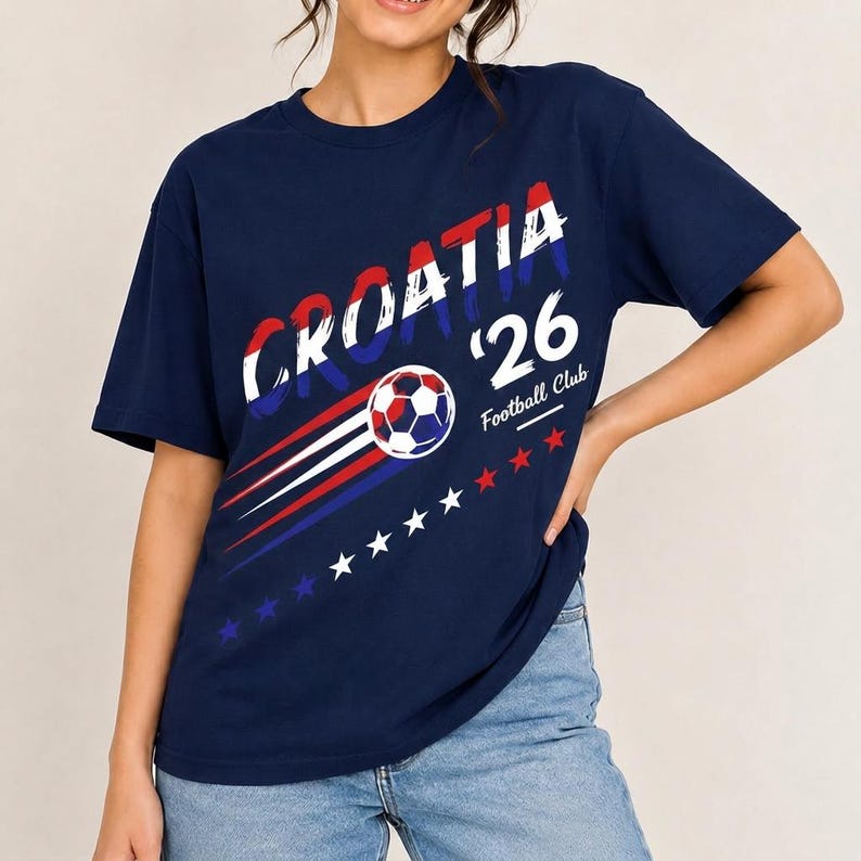 May include: A navy blue t-shirt featuring the text CROATIA in a distressed red, white, and blue font. Below the text is a soccer ball graphic with motion lines, the number 26, the words Football Club, and a row of small red, white, and blue stars.